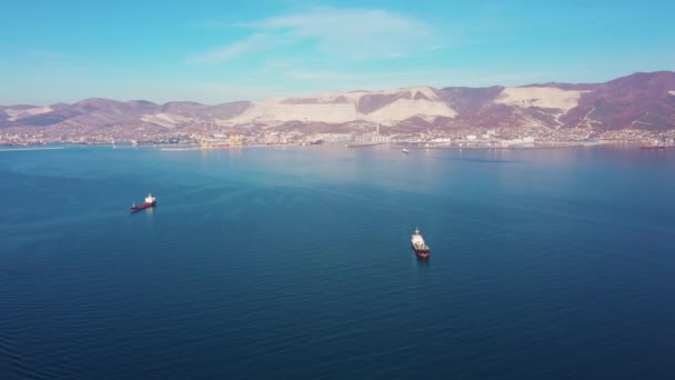 Luftaufnahme, Schiffe treiben auf ruhiger blauer Meeresoberfläche gegen hügelige Küste — Stockvideo