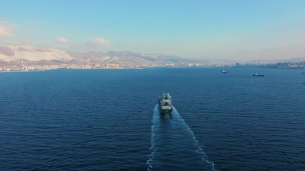 Vista aérea tras el ultra gran buque de carga en el mar sale del puerto al atardecer — Vídeos de Stock