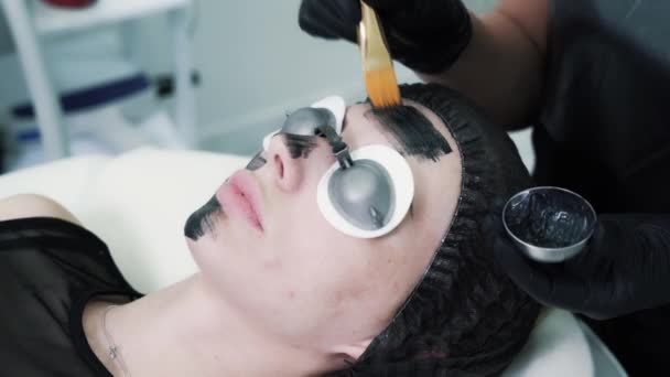 Beauty master maakt een carbon masker voor een mooie jonge klant — Stockvideo