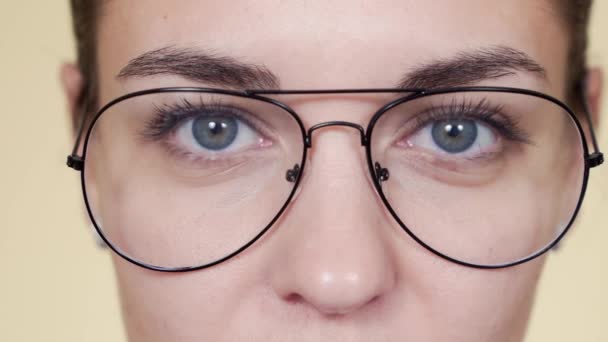 Крупным планом лицо молодой женщины в очках, смотрящей в камеру, моргающей — стоковое видео