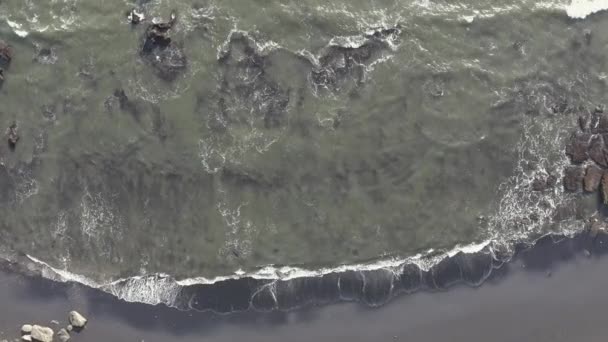 Vista aérea poderosas olas oceánicas en la playa volcánica negra estrellándose y espumando . — Vídeo de stock