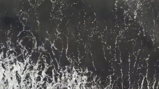 Aerial view powerful ocean waves at black volcanic beach crashing and foaming. — Stock Video