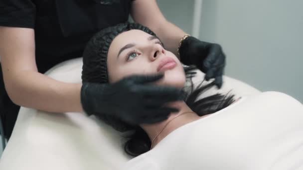 Mãos de jovem esteticista estão fazendo relaxante rosto e pescoço massagem — Vídeo de Stock