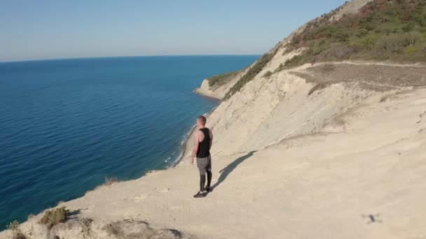 Flygfoto av människan står på toppen av berget nära klippan, vacker utsikt över havet — Stockvideo