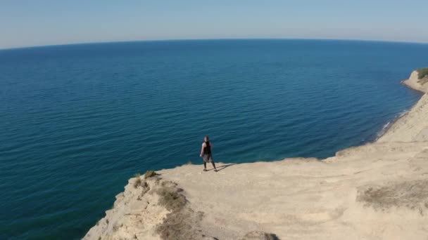Vista aérea do homem treinando com bandas elásticas no topo da montanha com vista para o mar — Vídeo de Stock