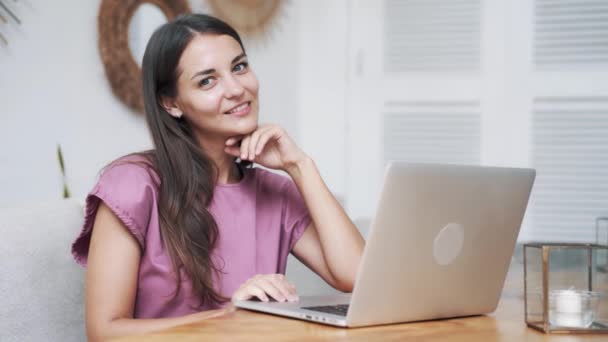 Retrato hermosa chica sentada en la cafetería con el ordenador portátil, mirando a la cámara, sonriendo — Vídeos de Stock