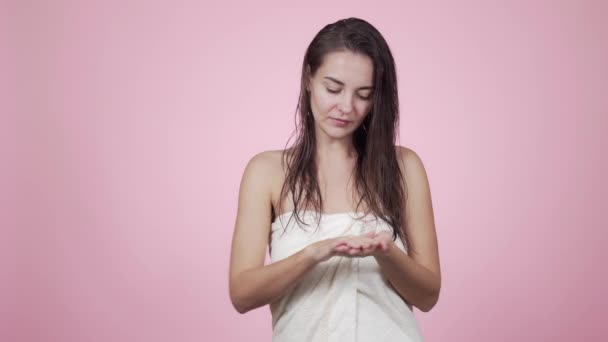 Mulher em toalha aplica óleo para cabelos molhados após o banho isolado em fundo rosa — Vídeo de Stock