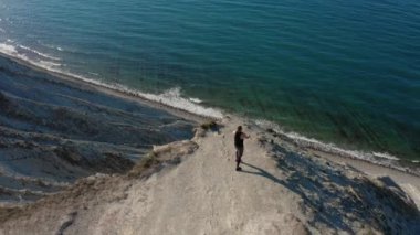 Uçurumun tepesinde lastik bantlarla hava manzaralı adam eğitimi, güzel bir deniz manzarası.
