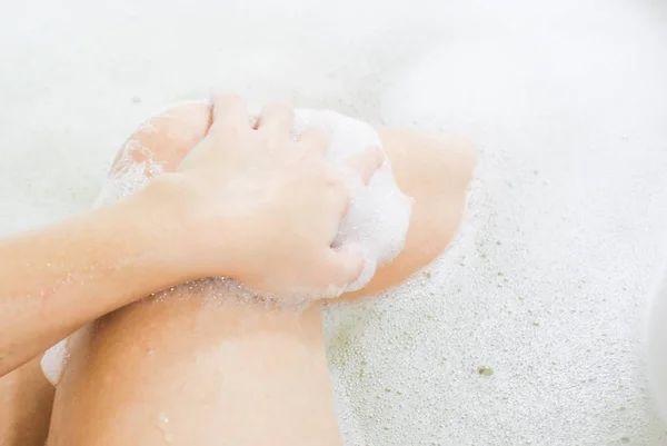 Women's slender legs in a bath with fragrant foam — Stock Photo, Image