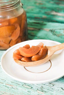 Ahşap yeşil arka plan üzerinde beyaz bir plaka üzerinde bir tahta kaşık üzerinde olgun armut kokusu taze reçel