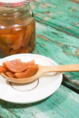 Güzel kokulu taze tatlı portakal reçeli olgun sulu armut üzerinden. Dilimlenmiş yeşil ahşap arka plan üzerinde beyaz bir plaka üzerinde bir tahta kaşık, armut ve armut suyu