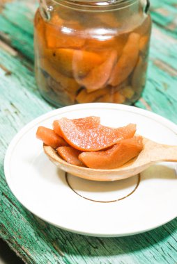 Güzel kokulu taze tatlı portakal reçeli olgun sulu armut üzerinden. Dilimlenmiş yeşil ahşap arka plan üzerinde beyaz bir plaka üzerinde bir tahta kaşık, armut ve armut suyu