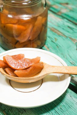 Güzel kokulu taze tatlı portakal reçeli olgun sulu armut üzerinden. Dilimlenmiş yeşil ahşap arka plan üzerinde beyaz bir plaka üzerinde bir tahta kaşık, armut ve armut suyu