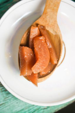 Güzel kokulu taze tatlı portakal reçeli olgun sulu armut üzerinden. Dilimlenmiş yeşil ahşap arka plan üzerinde beyaz bir plaka üzerinde bir tahta kaşık, armut ve armut suyu