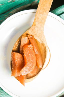 Güzel kokulu taze tatlı portakal reçeli olgun sulu armut üzerinden. Dilimlenmiş yeşil ahşap arka plan üzerinde beyaz bir plaka üzerinde bir tahta kaşık, armut ve armut suyu