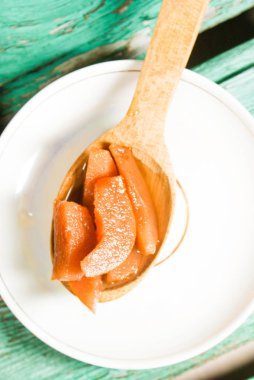 Güzel kokulu taze tatlı portakal reçeli olgun sulu armut üzerinden. Dilimlenmiş yeşil ahşap arka plan üzerinde beyaz bir plaka üzerinde bir tahta kaşık, armut ve armut suyu