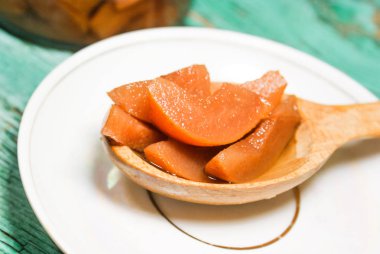 Güzel kokulu taze tatlı portakal reçeli olgun sulu armut üzerinden. Dilimlenmiş yeşil ahşap arka plan üzerinde beyaz bir plaka üzerinde bir tahta kaşık, armut ve armut suyu