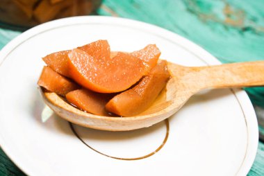 Güzel kokulu taze tatlı portakal reçeli olgun sulu armut üzerinden. Dilimlenmiş yeşil ahşap arka plan üzerinde beyaz bir plaka üzerinde bir tahta kaşık, armut ve armut suyu