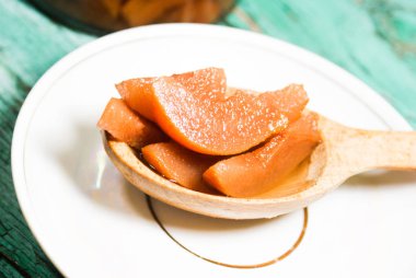 Güzel kokulu taze tatlı portakal reçeli olgun sulu armut üzerinden. Dilimlenmiş yeşil ahşap arka plan üzerinde beyaz bir plaka üzerinde bir tahta kaşık, armut ve armut suyu