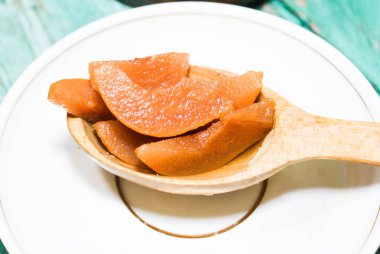 Güzel kokulu taze tatlı portakal reçeli olgun sulu armut üzerinden. Dilimlenmiş yeşil ahşap arka plan üzerinde beyaz bir plaka üzerinde bir tahta kaşık, armut ve armut suyu