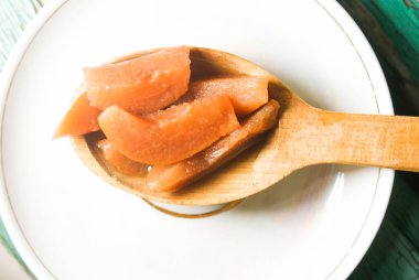 Güzel kokulu taze tatlı portakal reçeli olgun sulu armut üzerinden. Dilimlenmiş yeşil ahşap arka plan üzerinde beyaz bir plaka üzerinde bir tahta kaşık, armut ve armut suyu