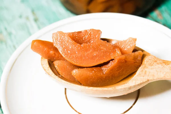 Ahşap yeşil arka plan üzerinde beyaz bir plaka üzerinde bir tahta kaşık üzerinde olgun armut kokusu taze reçel