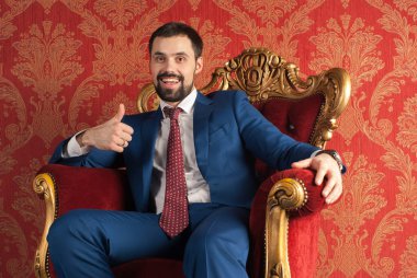 Zarafet ve stil. Smokin ve kırmızı kravat takan yakışıklı genç adam portresi.