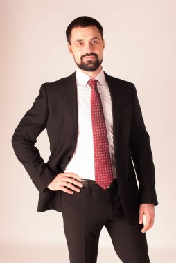 Zarafet ve stil. Smokin ve kırmızı kravat takan yakışıklı genç adam portresi.