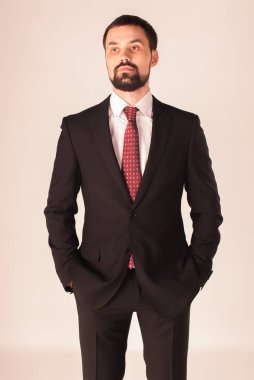 Zarafet ve stil. Smokin ve kırmızı kravat takan yakışıklı genç adam portresi.