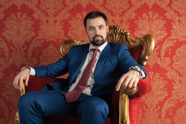 Zarafet ve stil. Smokin ve kırmızı kravat takan yakışıklı genç adam portresi.