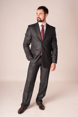 Zarafet ve stil. Smokin ve kırmızı kravat takan yakışıklı genç adam portresi.