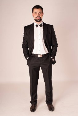 Zarafet ve stil. Smokin ve kırmızı kravat takan yakışıklı genç adam portresi.