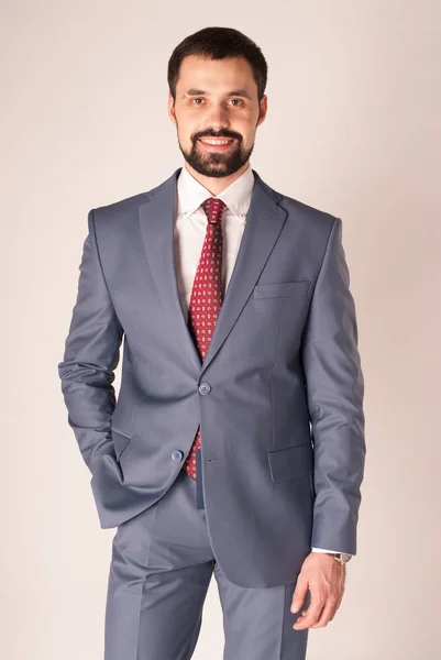 Zarafet ve stil. Smokin ve kırmızı kravat takan yakışıklı genç adam portresi.