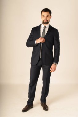 Zarafet ve stil. Smokin ve kırmızı kravat takan yakışıklı genç adam portresi.