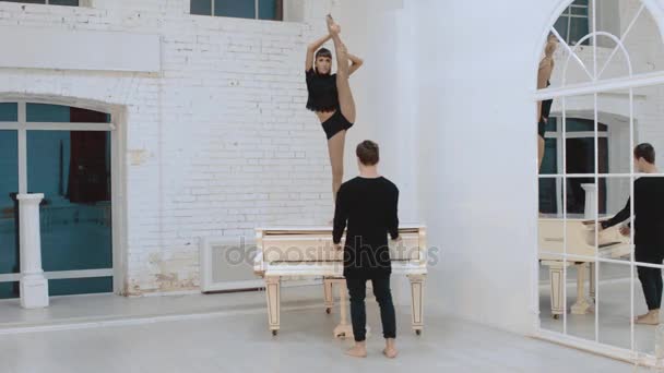 Kvinnliga och manliga gymnaster som värmer upp på piano — Stockvideo
