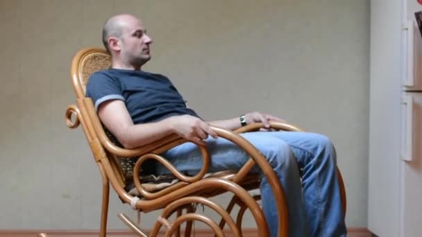 Молодой человек расслабляется на кресле-качалке — стоковое видео