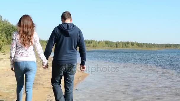 Jong koppel lopen naar de Bank van de rivier, Man en vrouw hand in hand buiten In herfst Park natuurlijke licht Slow Motion 60 — Stockvideo