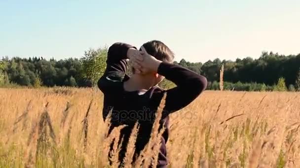 Jonge Man lopen en verhogen van handen in het veld — Stockvideo