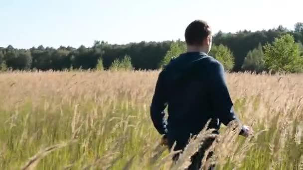 Jonge Man lopen en verhogen van handen in het veld — Stockvideo