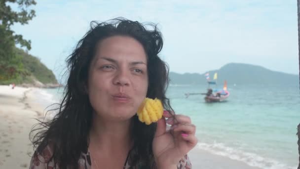 Primer plano chica come fruta de piña en la playa de arena, Bon isla Tailandia, en el fondo azul mar — Vídeos de Stock