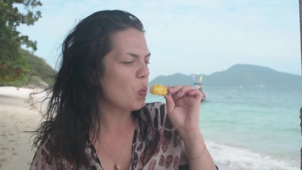 Primer plano chica come fruta de piña en la playa de arena, Bon isla Tailandia, en el fondo azul mar — Vídeos de Stock