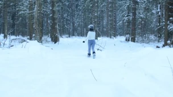 滑稽顽皮的女孩抛出雪球直接到相机 白色飞溅周围飞 在雪地里闲逛 在树林里漫步 雪花缓缓落下 — 图库视频影像