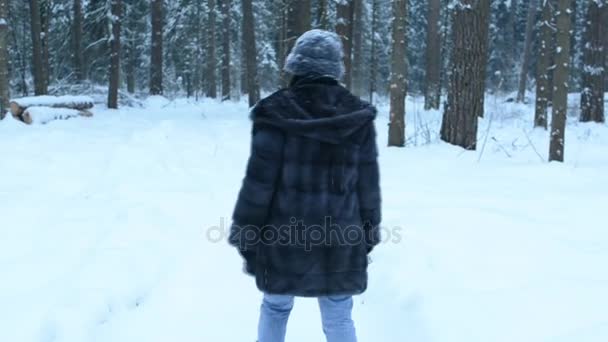 面白い遊び心のある女の子は、白い水しぶきのまわりで飛ぶカメラにまっすぐ雪だるまをスローします。雪と森の中で散歩の周りじゃなくて。雪がゆっくりと落ちる. — ストック動画