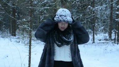 Oynak kız karda dalga geçmeyi ve ormanda yürür. Kar sonbahar aşağı.