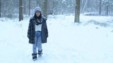 Oynak kız karda dalga geçmeyi ve ormanda yürür. Kar sonbahar aşağı.