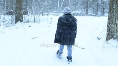 Oynak kız karda dalga geçmeyi ve ormanda yürür. Kar sonbahar aşağı.