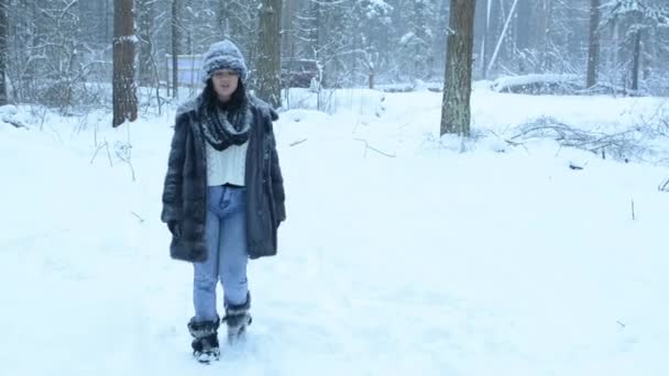 Funny playful girl fooling around in the snow and walks in the woods. Snow fall down. — Stock Video