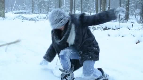 Забавная игривая девчонка валяет дурака в снегу и гуляет по лесу. Снег падает . — стоковое видео