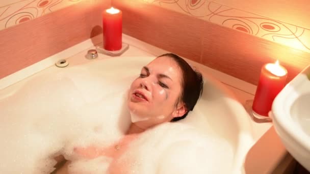 美丽的年轻女子在按摩浴缸温泉度假村放松 浪漫的蜡烛背景 沉浸在泡沫中 哭泣和欢笑 — 图库视频影像