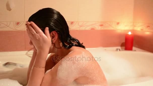 美丽的年轻女子在按摩浴缸温泉度假村放松 浪漫的蜡烛背景 沉浸在泡沫中 哭泣和欢笑 — 图库视频影像
